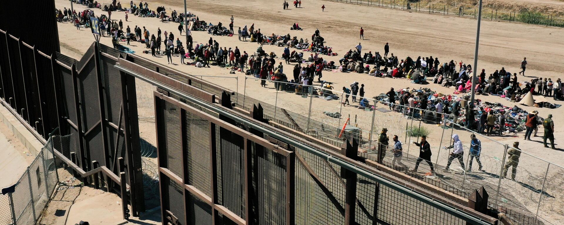 Uma imagem aérea mostra migrantes esperando ao longo do muro da fronteira para se renderem aos agentes da Patrulha de Fronteira da Alfândega e Proteção de Fronteiras dos EUA (CBP, na sigla em inglês) para processamento de pedidos de imigração e asilo após cruzarem o Rio Grande para os Estados Unidos, na fronteira EUA-México, em El Paso, Texas, 10 de maio de 2023 - Sputnik Brasil, 1920, 26.02.2024