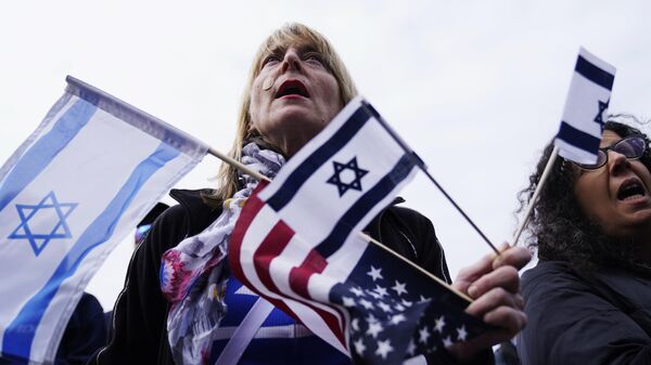 Um apoiador segura bandeiras israelenses e americanas em um evento de solidariedade em Glencoe, Illinois, 10 de outubro de 2023 - Sputnik Brasil