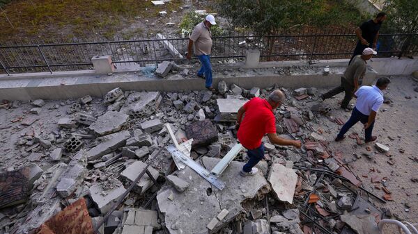Homens libaneses verificam uma casa danificada que foi atingida por bombardeios israelenses na vila de Duhaira, na fronteira com Israel. Líbano, 12 de outubro de 2023 - Sputnik Brasil