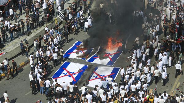 Iraquianos queimam bandeiras israelenses durante manifestação em apoio aos palestinos na Faixa de Gaza. Bagdá, Iraque, 13 de outubro de 2023 - Sputnik Brasil