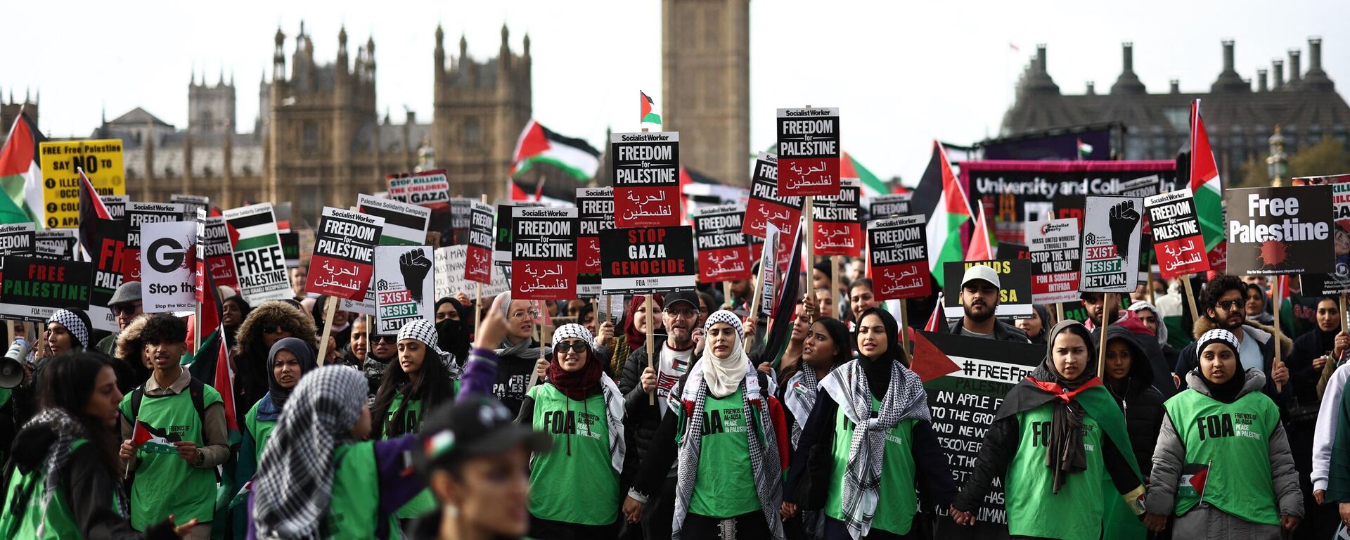 Manifestantes seguram cartazes enquanto caminham pela Ponte de Westminster com o Palácio de Westminster, sede das Casas do Parlamento, durante uma 'Marcha pela Palestina' em Londres, em 28 de outubro de 2023 - Sputnik Brasil, 1920, 28.10.2023