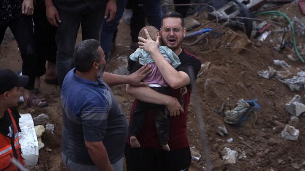 Um homem palestino chora enquanto segura uma criança morta que foi encontrada sob os escombros de um prédio destruído após ataques aéreos israelenses no campo de refugiados de Nusseirat, centro da Faixa de Gaza, 31 de outubro de 2023 - Sputnik Brasil