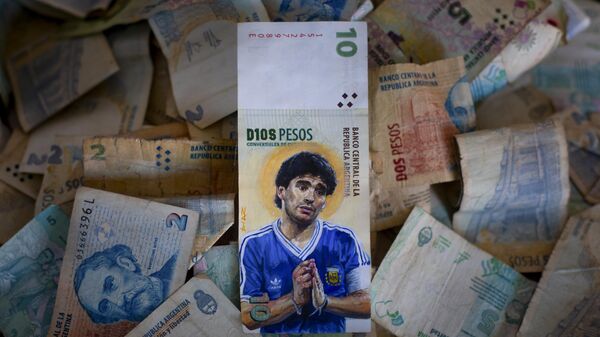 Uma peça arte do artista Sergio Díaz apresenta a falecida lenda do futebol Diego Maradona com as mãos envoltas em um rosário e uma auréola atrás da cabeça, pintada em uma nota de dez pesos argentinos em 9 de setembro de 2023 - Sputnik Brasil