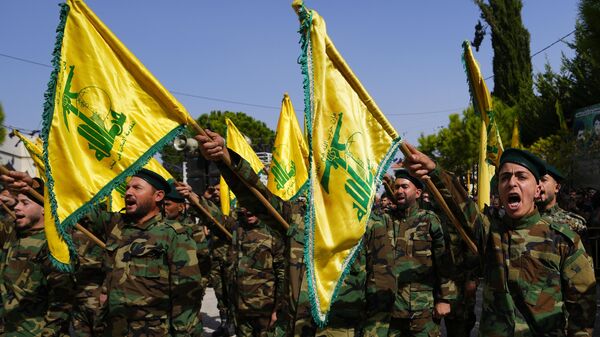 Combatentes do Hezbollah levantam a bandeira de seu grupo e entoam gritos de guerra enquanto assistem ao cortejo fúnebre do combatente do Hezbollah Bilal Nemr Rmeiti, morto por bombardeios israelenses, em 22 de outubro de 2023 - Sputnik Brasil