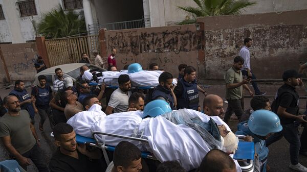 Palestinos, incluindo alguns jornalistas, carregam os corpos de dois repórteres palestinos, Mohammed Soboh e Said al-Tawil, mortos por um ataque aéreo israelense na cidade de Gaza, em 10 de outubro de 2023 - Sputnik Brasil