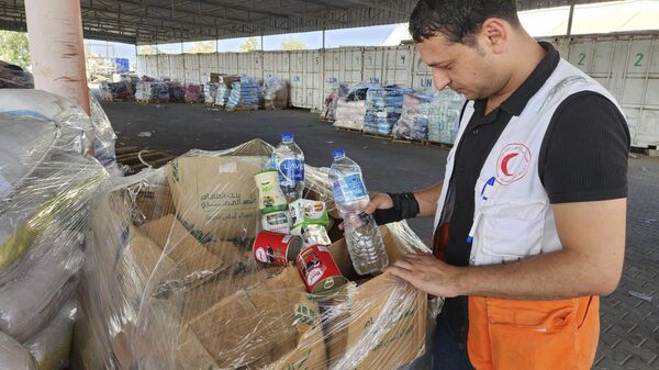 Trabalhadores das Nações Unidas e do Crescente Vermelho preparam ajuda para distribuição aos palestinos no armazém da UNRWA, em Deir Al-Balah. Faixa de Gaza, 23 de outubro de 2023 - Sputnik Brasil