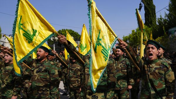Combatentes do Hezbollah levantam a bandeira do grupo e gritam palavras de ordem enquanto assistem ao cortejo fúnebre de combatente morto por bombardeios israelenses, em Majadel. Líbano, 22 de outubro de 2023 - Sputnik Brasil