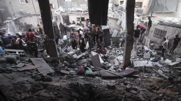 Palestinos em meio à destruição provocada por ataque aéreo israelense em campo de refugiados na Faixa de Gaza. Khan Yunis, 13 de novembro de 2023 - Sputnik Brasil