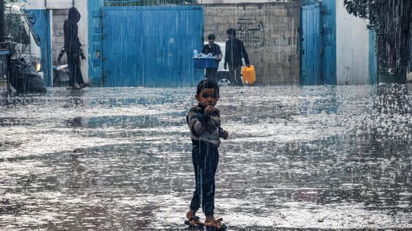 Um menino fica na chuva em uma escola administrada pela Agência das Nações Unidas de Assistência aos Refugiados da Palestina no Próximo Oriente (UNRWA, na sigla em inglês), em Rafah. Faixa de Gaza, 14 de novembro de 2023 - Sputnik Brasil