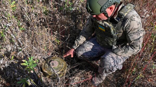 Chefe do fundo de caridade Desminagem da Ucrânia, Roman Hekalyuk, examina uma mina antitanque TM-62M perto da cidade de Derhachi, região de Kharkiv, em 1º de outubro de 2023 - Sputnik Brasil
