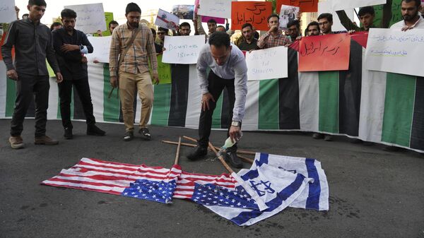 Manifestante derrama gasolina nas bandeiras de Israel e dos EUA, antes de atear fogo a elas, durante um protesto em Teerã contra a viagem de Biden ao Oriente Médio. Irã, 16 de julho de 2022 - Sputnik Brasil