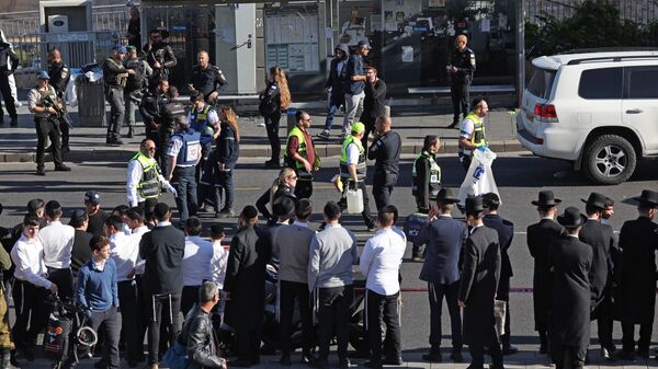 Pessoas observam enquanto a força de segurança israelense e as equipes de resgate inspecionam o local de um tiroteio matinal em Jerusalém, em 30 de novembro de 2023 - Sputnik Brasil