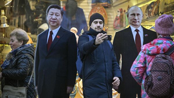 As pessoas passam por imagens de papelão representando o presidente chinês Xi Jinping (E) e seu homólogo russo Vladimir Putin na turística rua Arbat, no centro de Moscou, em 15 de novembro de 2023 - Sputnik Brasil