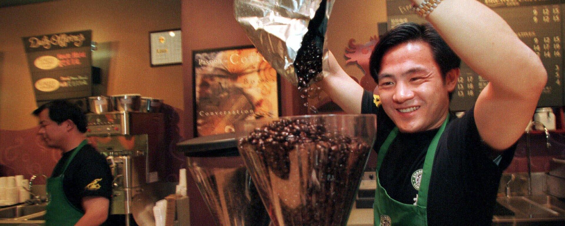 Funcionário despeja grãos de café em moedor na abertura da primeira loja de café da marca americana Starbucks na China, em 11 de janeiro de 1999 - Sputnik Brasil, 1920, 08.12.2023