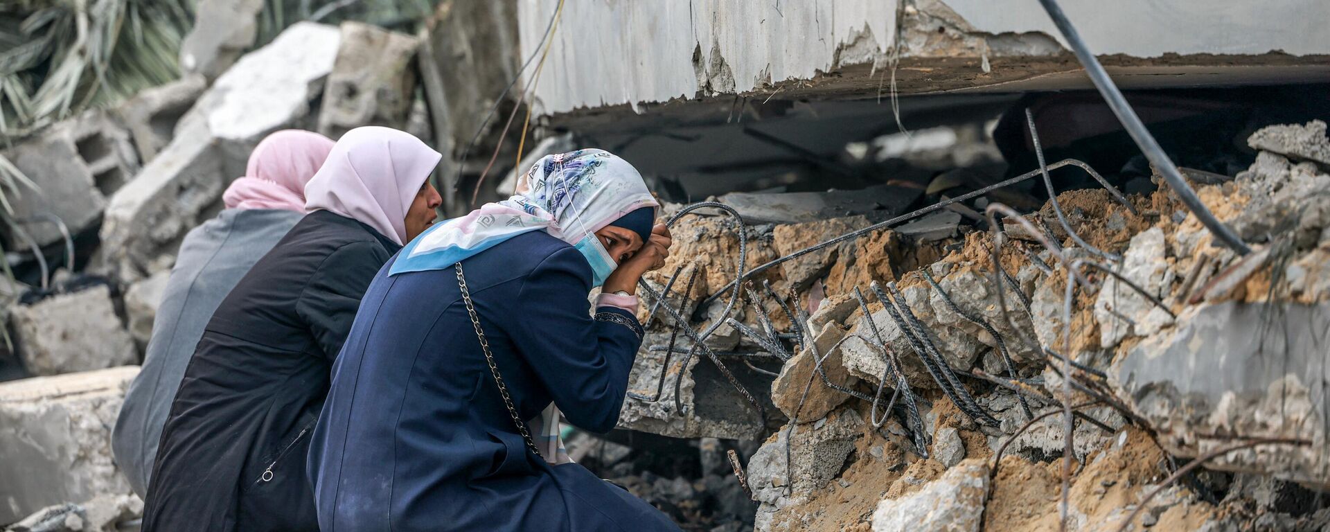 Mulheres palestinas choram onde se acredita que um parente esteja preso nos escombros após o bombardeio israelense em Rafah, no sul da Faixa de Gaza, em 21 de dezembro de 2023 - Sputnik Brasil, 1920, 23.12.2023
