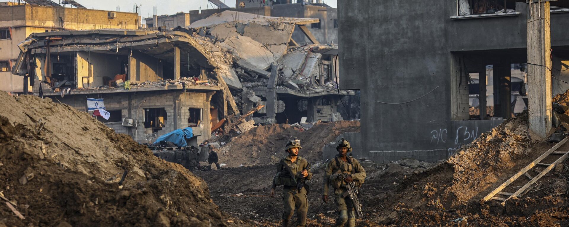 Soldados israelenses passando por edifícios danificados durante uma operação militar no norte da Faixa de Gaza, 19 de dezembro de 2023 - Sputnik Brasil, 1920, 24.12.2023