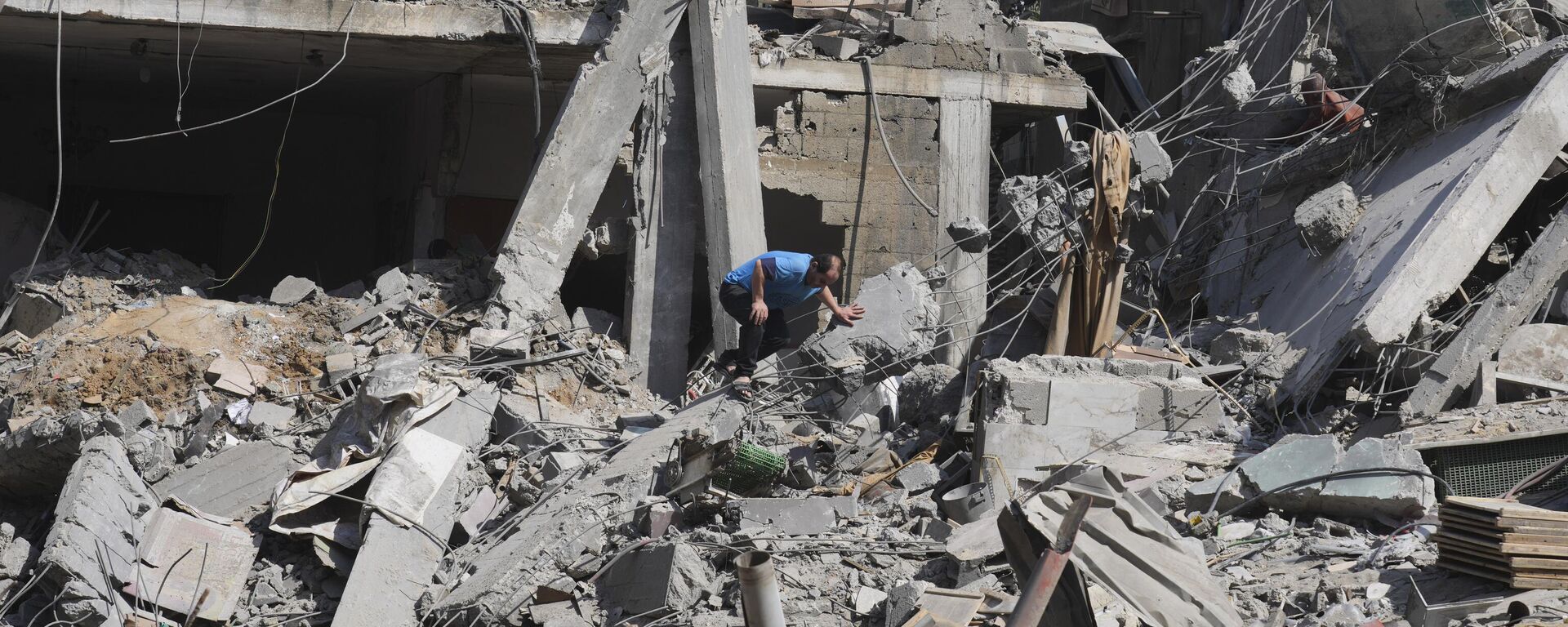 Palestino sai de prédio destruído por bombardeio israelense na Faixa de Gaza, no campo de refugiados Al-Maghazi, em Deir al-Balah, em 25 de outubro de 2023 - Sputnik Brasil, 1920, 02.05.2024