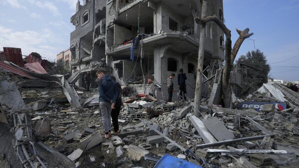 Famílias em meio aos destroços após bombardeios intensos das Forças de Defesa de Israel (FDI) contra campo de refugiados em Maghazi. Faixa de Gaza, 25 de dezembro de 2023 - Sputnik Brasil