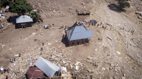 Sobreviventes caminham entre escombros próximos a edifícios destruídos após as enchentes na vila de Nyamukubi, província de Kivu do Sul, na República Democrática do Congo, 8 de maio de 2023 - Sputnik Brasil