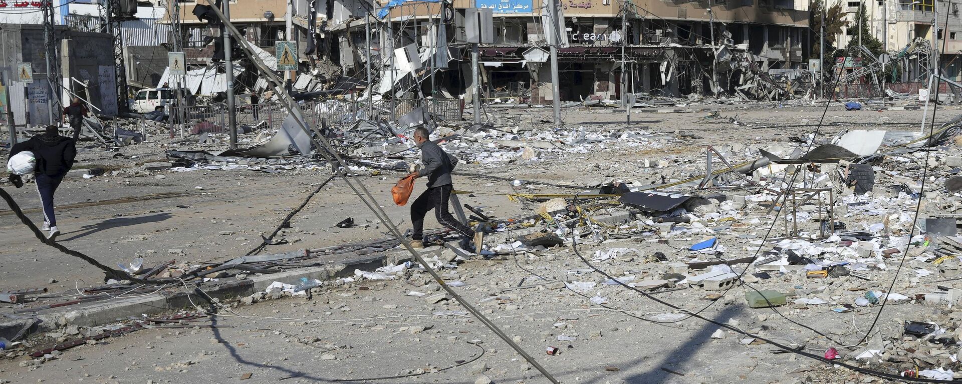 Palestinos passam pela destruição causada por um bombardeio israelense no campo de refugiados de Nusseirat. Faixa de Gaza, 16 de janeiro de 2024 - Sputnik Brasil, 1920, 18.02.2024