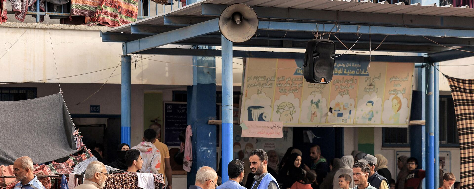 Pessoas caminham no parquinho de uma escola administrada pela Agência das Nações Unidas de Assistência e Obras para os Refugiados da Palestina (UNRWA), que foi convertida em um abrigo para palestinos deslocados em Khan Yunis, no sul da Faixa de Gaza, em 25 de outubro de 2023 - Sputnik Brasil, 1920, 25.02.2024