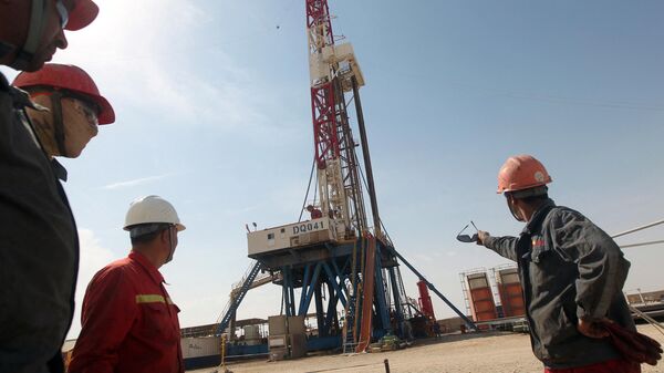 Funcionários da Gazprom observam uma plataforma de perfuração da empresa Gazprom em um campo petrolífero perto da cidade iraquiana de Badra, ao sul de Bagdá, em 18 de outubro de 2012 - Sputnik Brasil