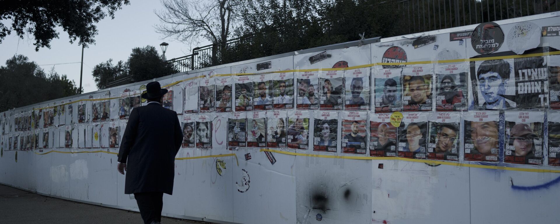 Homem observa mural com retratos de israelenses que foram sequestrados durante o ataque sem precedentes do Hamas contra Israel, em 7 de outubro de 2023. Jerusalém, 30 de janeiro de 2024 - Sputnik Brasil, 1920, 16.02.2024