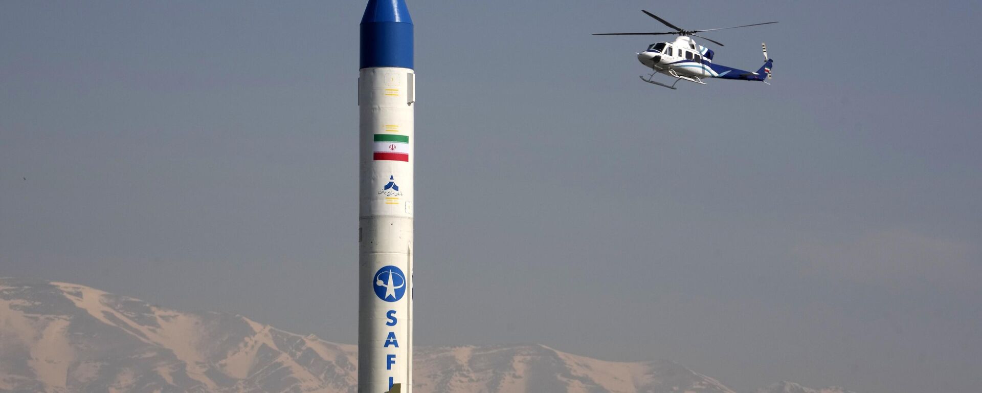 Helicóptero sobrevoa porta-satélites iraniano exibido durante comício anual em comemoração à Revolução Islâmica iraniana de 1979 em Teerã, Irã, 11 de fevereiro de 2024 - Sputnik Brasil, 1920, 15.01.2026