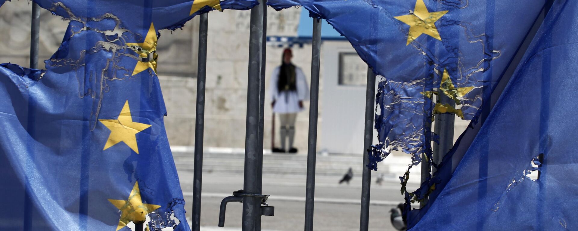 Guarda presidencial grega enquadrada pelos restos de uma bandeira da União Europeia, parcialmente queimada por manifestantes em Atenas, em 1º de maio de 2013 - Sputnik Brasil, 1920, 15.02.2024