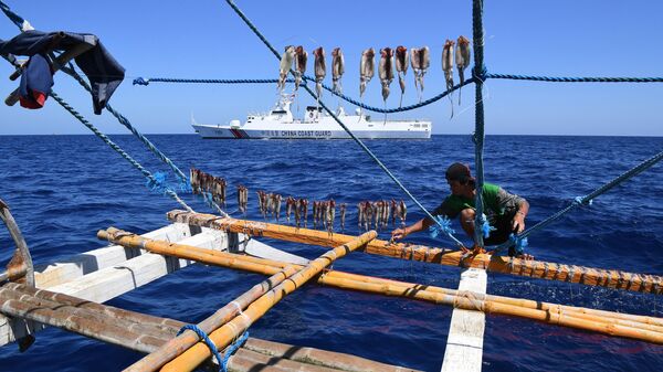 Pescador das Filipinas manejando barco de pesca enquanto um navio da Guarda Costeira chinesa monitora perto do Scarborough Shoal, controlado pela China, em águas disputadas no mar do Sul da China, 15 de fevereiro de 2024 - Sputnik Brasil