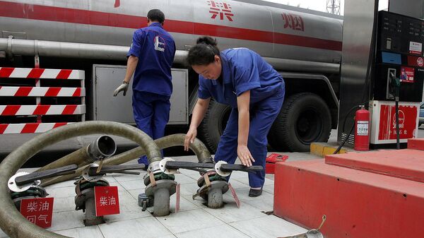 Trabalhador chinês de uma das maiores empresas de petróleo da China, a Sinopec, manuseia mangueiras após entregar gasolina em um posto em Pequim, China. - Sputnik Brasil