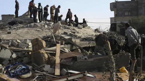 Palestinos observam destruição em um prédio após um ataque israelense em Rafah. Faixa de Gaza, 3 de março de 2024 - Sputnik Brasil