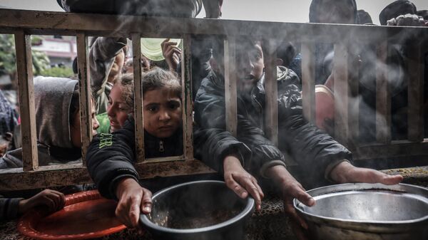 Crianças palestinas deslocadas se reúnem para receber comida em uma escola pública em Rafah, no sul da Faixa de Gaza, em 19 de fevereiro de 2024 - Sputnik Brasil