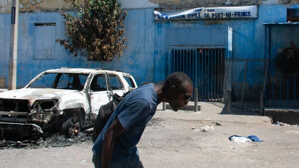 Um homem sai da área da prisão e abaixa a cabeça por causa do tiroteio nas proximidades, em Porto Príncipe, Haiti, 4 de março de 2024 - Sputnik Brasil