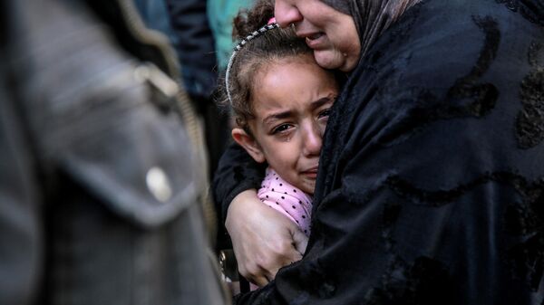 Mulher palestina abraça criança enquanto choram pelos parentes mortos no bombardeio israelense em frente ao necrotério do hospital Al-Shifa, na cidade de Gaza, em 15 de março de 2024 - Sputnik Brasil