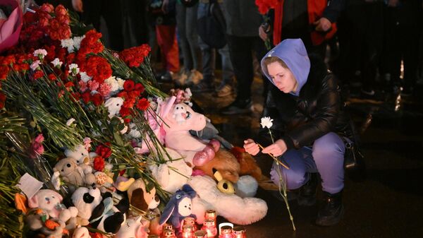 Mulher acende uma vela em um memorial feito por residentes locais, perto do teatro Crocus, em memória às vítimas do ataque terrorista. Rússia, 23 de março de 2024 - Sputnik Brasil