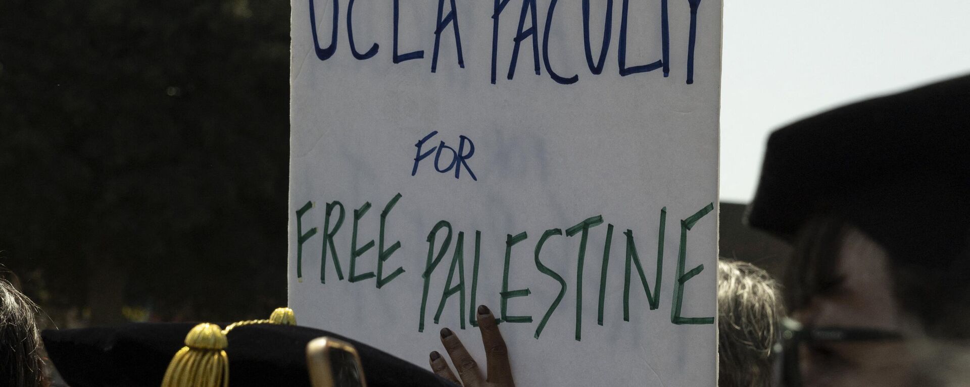 Manifestante segura cartaz dizendo Faculdade UCLA pela Palestina Livre enquanto membros da faculdade e da equipe da Universidade de Califórnia de Los Angeles (UCLA, na sigla em inglês) se manifestam ao lado de acampamento pró-palestino no campus da universidade em Los Angeles, Califórnia, EUA, 1º de maio de 2024 - Sputnik Brasil, 1920, 04.05.2024