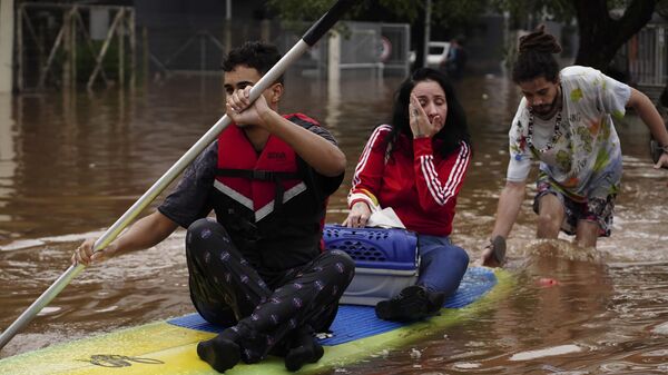 Moradores usam prancha de surfe para se locomover por bairro inundado por fortes chuvas, em Canoas. Rio Grande do Sul, 4 de maio de 2024 - Sputnik Brasil
