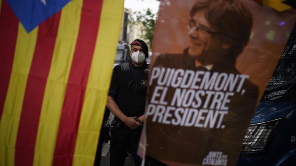 Policial atrás de uma bandeira da Catalunha e uma faixa com a imagem do ex-líder catalão Carles Puigdemont com a mensagem Puigdemont, nosso líder. Espanha, 24 de setembro de 2021 - Sputnik Brasil