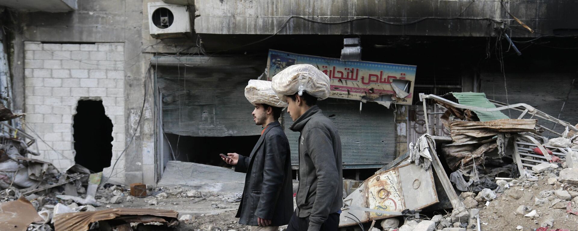Homens sírios carregam sacos de pão na cabeça enquanto caminham de volta para suas casas no bairro de Bustan al-Qasr, no leste de Aleppo. Síria, 20 de janeiro de 2017 - Sputnik Brasil, 1920, 15.05.2024