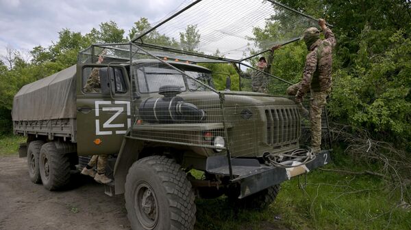 Militares das Forças Armadas da Rússia cobrem veículo militar com rede de camuflagem, foto publicada em 16 de maio de 2024 - Sputnik Brasil