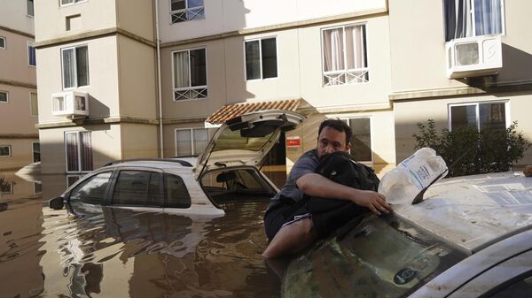 Homem se apoia em carro enquanto tenta retornar ao seu prédio inundado após fortes chuvas em Canoas (RS), em 9 de maio de 2024 - Sputnik Brasil