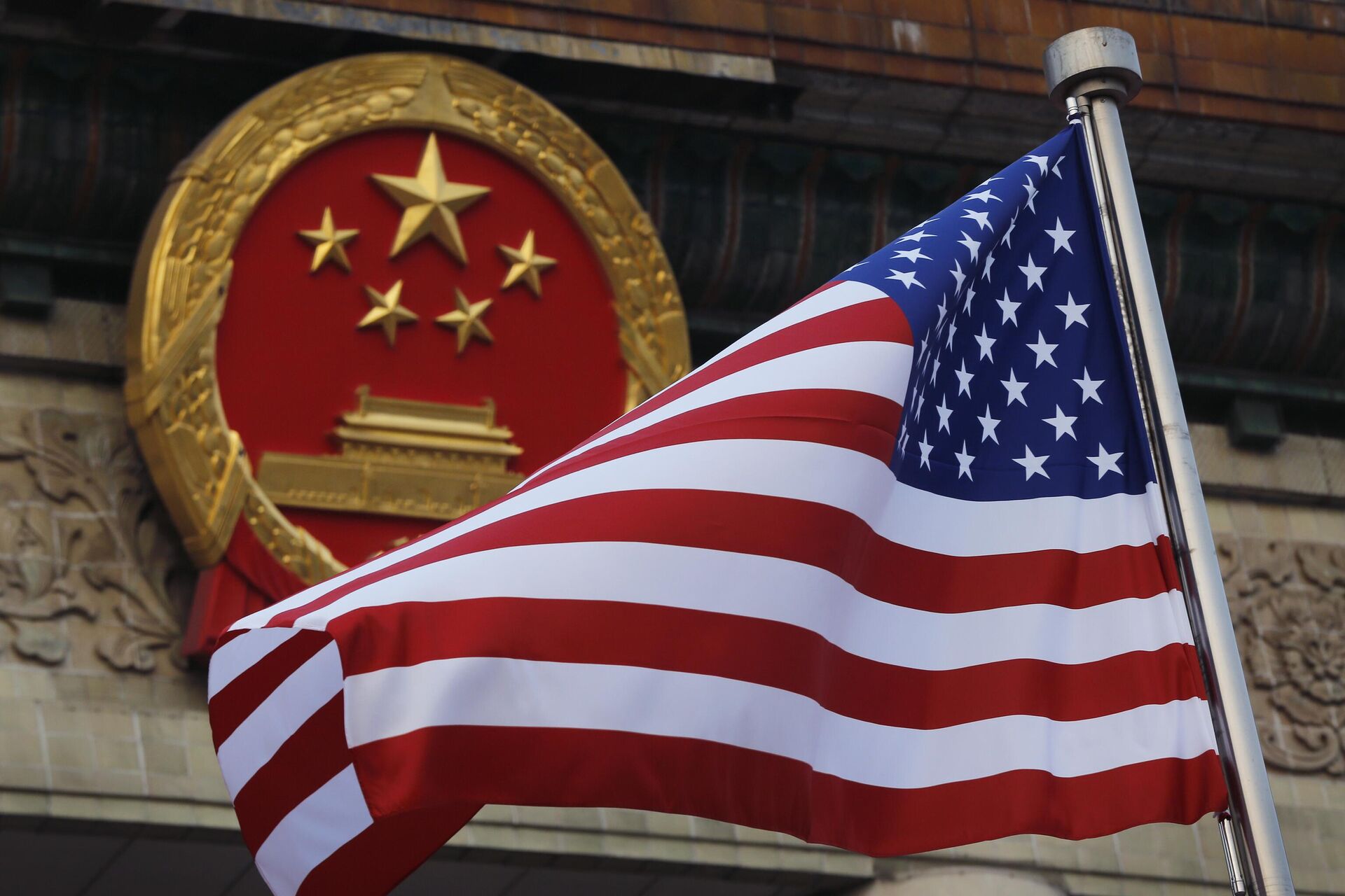 Uma bandeira americana hasteada ao lado do emblema nacional chinês fora do Grande Salão do Povo em Pequim