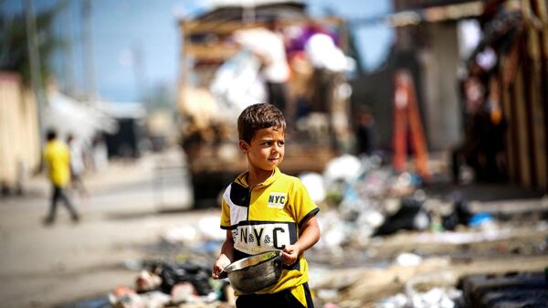 Um menino palestino segura uma panela de comida enquanto as pessoas deixam um campo em Rafah para áreas mais seguras no centro de Gaza em 15 de maio de 2024 - Sputnik Brasil