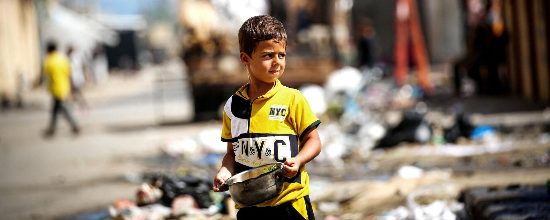 Um menino palestino segura uma panela de comida enquanto as pessoas deixam um campo em Rafah para áreas mais seguras no centro de Gaza em 15 de maio de 2024 - Sputnik Brasil, 1920, 25.05.2024
