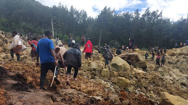Grupo de pessoas atravessa uma área afetada por um deslizamento de terra para chegar à outra parte da aldeia de Yambali, em Papua-Nova Guiné. 24 de maio de 2024 - Sputnik Brasil