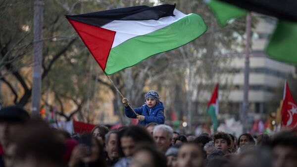 Menino agita bandeira palestina enquanto manifestantes marcham durante protesto em apoio aos palestinos e pedindo um cessar-fogo imediato em Gaza. Barcelona, Espanha, 20 de janeiro de 2024 - Sputnik Brasil