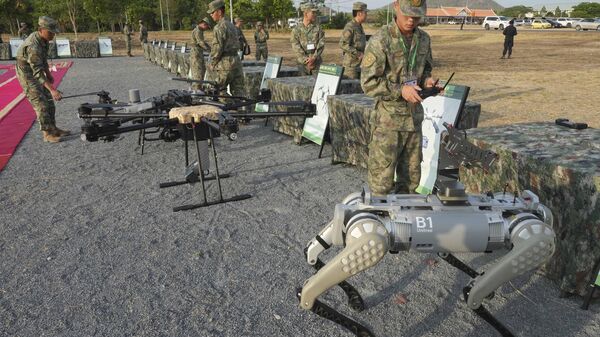 Um militar chinês, à direita, testa uma metralhadora equipada em um cão-robô antes de participar do exercício militar Golden Dragon na vila de Svay Chok, província de Kampong Chhnang, ao norte de Phnom Penh, Camboja, 16 de maio de 2024 - Sputnik Brasil