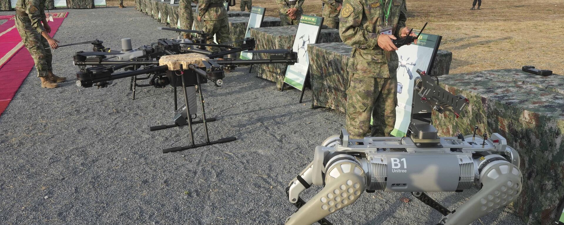 Um militar chinês, à direita, testa uma metralhadora equipada em um cão-robô antes de participar do exercício militar Golden Dragon na vila de Svay Chok, província de Kampong Chhnang, ao norte de Phnom Penh, Camboja, 16 de maio de 2024 - Sputnik Brasil, 1920, 28.05.2024