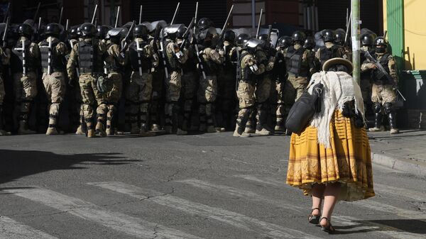 Mulher caminha em frente a militares na Praça Murillo, em La Paz. Bolívia, 26 de junho de 2024 - Sputnik Brasil